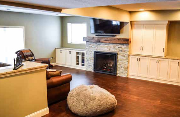 A basement remodel with a fireplace and custom cabinets. 