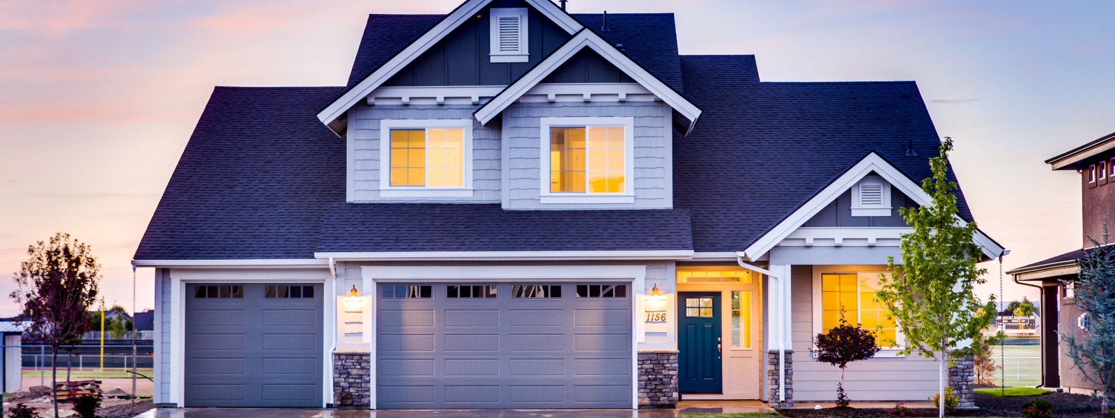 Exterior remodeling services image of a blue home at sunset with new siding, brick vaneer, and asphalt roof. 